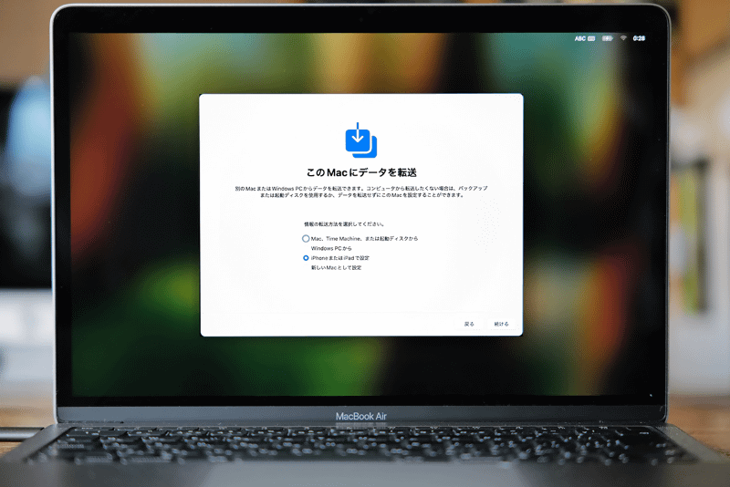 「設定アシスタント」で設定を進めていくと、「このMacにデータを転送」という移行アシスタントの画面が表示されます。[iPhoneまたはiPadで設定]を選んで[続ける]をクリックします
