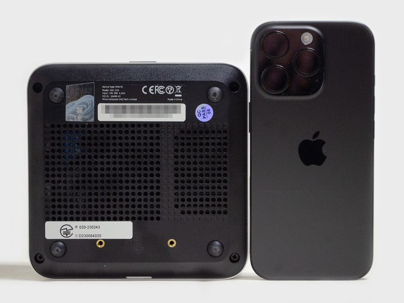 裏面。VESAマウンタ用ネジ穴2つ。サイズ比較用にiPhone 16 Proを置いてみた。ミニPCとしては標準的なサイズ