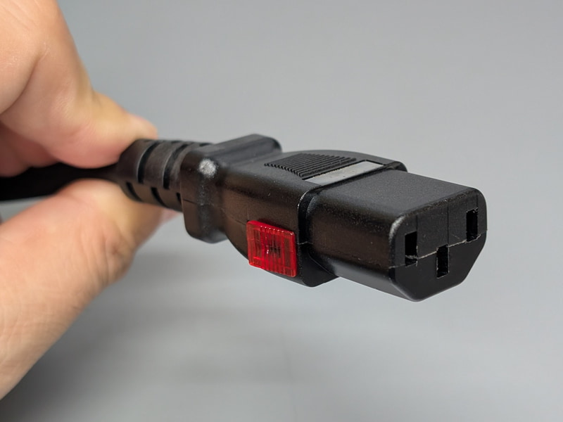 プラグはPCユーザーにはおなじみIEC60320 C13準拠の形状だが、側面に赤いつまみが見える