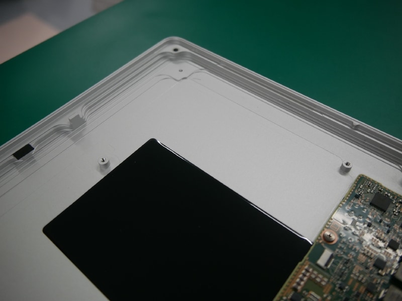 筐体の縁の部分は段差を持たせた構造により強度を高めている。アルミ切削加工ならばの構造。黒い部分は放熱用シート。大きなシートを採用し、アルミに熱を放出する