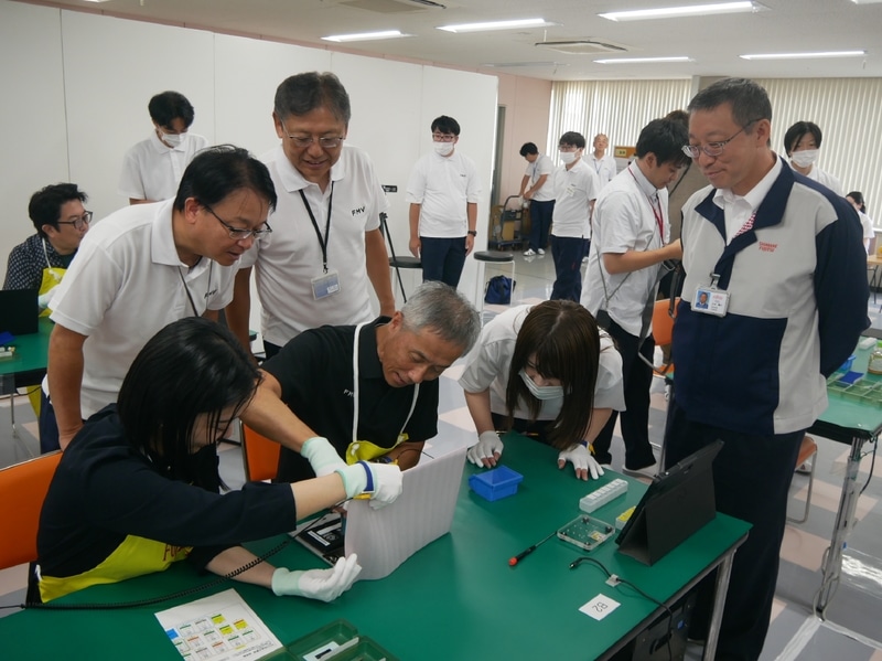 幹部が集合して高嶋執行役員常務の作業を見守る。(後列左から)島根富士通の山根淳副社長、島根富士通の宮下社長、FCCLの小中本部長代理