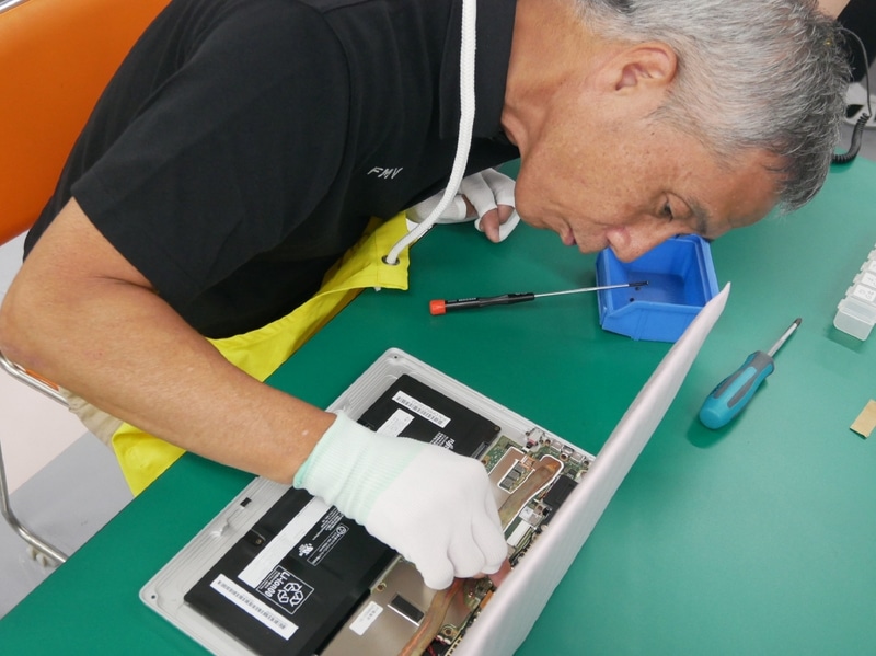 メインボードにディスプレイのケーブルを接続する。細かい作業に苦戦する高嶋執行役員常務