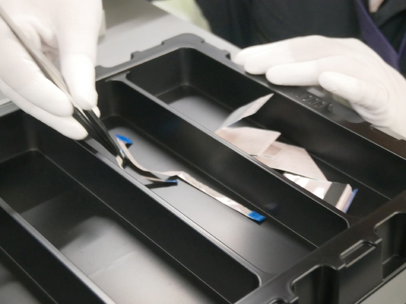 トレイに入れられた再生部品やフレキケーブルを使用する