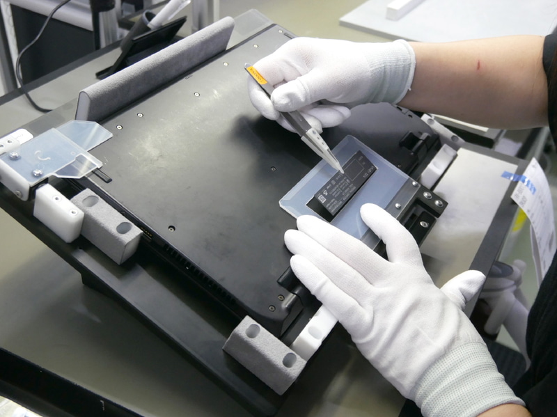 治具を使ってラベルを貼り付け。前のラベル跡が隠れるように少し大きめにするという工夫も