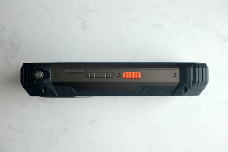 本体左側面。SIMカードスロットは爪で即座に引き出せる。また、プロジェクタのピント調節用ノブも見える。本体と同系統の色のボタンは音量で、オレンジのボタンは機能をカスタマイズ可能だ