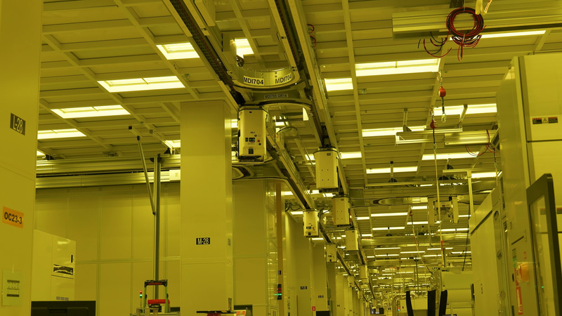 工場の中はこのようにAMHSが天井のレールからぶら下がって工場の中を移動している。Fab 12～Fab 52まですべて1つのレールでつながっており、その総距離は30マイルにも達するという。東京駅から江の島までの直線距離に匹敵する(出典: F52-Inside/B-roll、Intel)