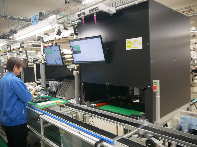 黒いボックスの中で内観検査ロボットが稼働し、部品が正しく取り付けられていることを自動で確認する