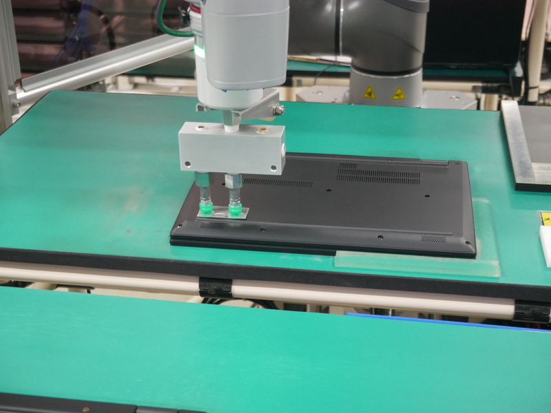 カメラで確認しながら、正しい位置に複数のラベルを貼付する。ロボットと人が協働している