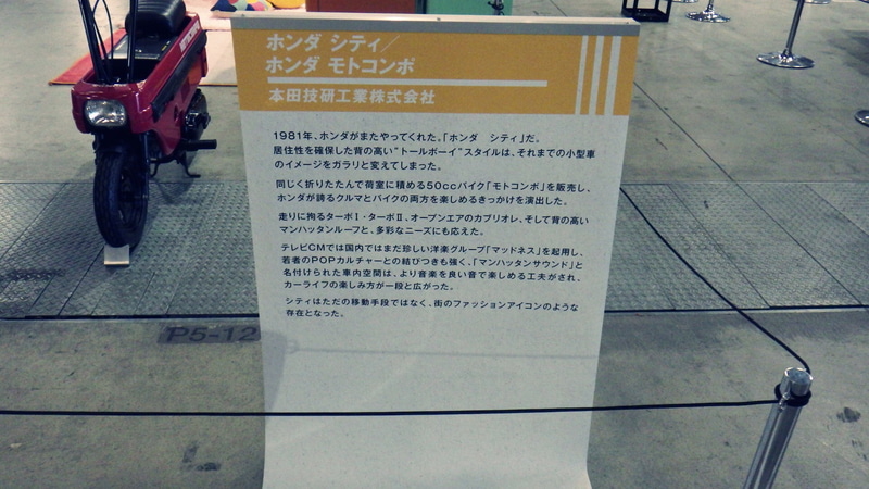 小型乗用車「シティ」と折りたたみ式原付きバイク「モトコンポ」の展示説明板。左奥の赤いバイクが「モトコンポ」。2025年10月30日に筆者が撮影
