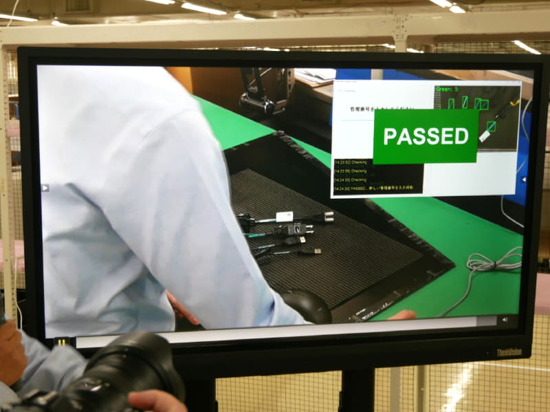 ラべルの数が多い案件の場合には、ラベル貼付工程をカメラの画像で確認しながら判断する。ケーブルへのラベル貼付にも対応する