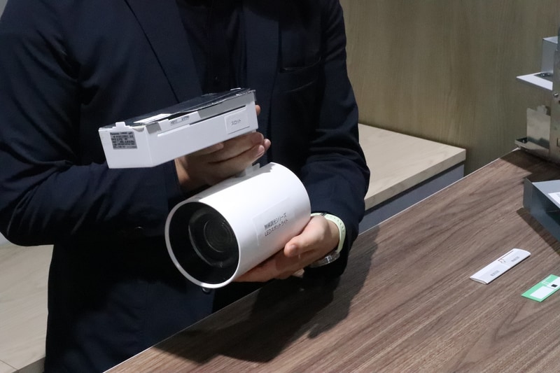 この製品は天井の照明用レールに取り付けるLEDスポットライト。四角い金属製のボックスの中に電源回路と無線回路が実装されている