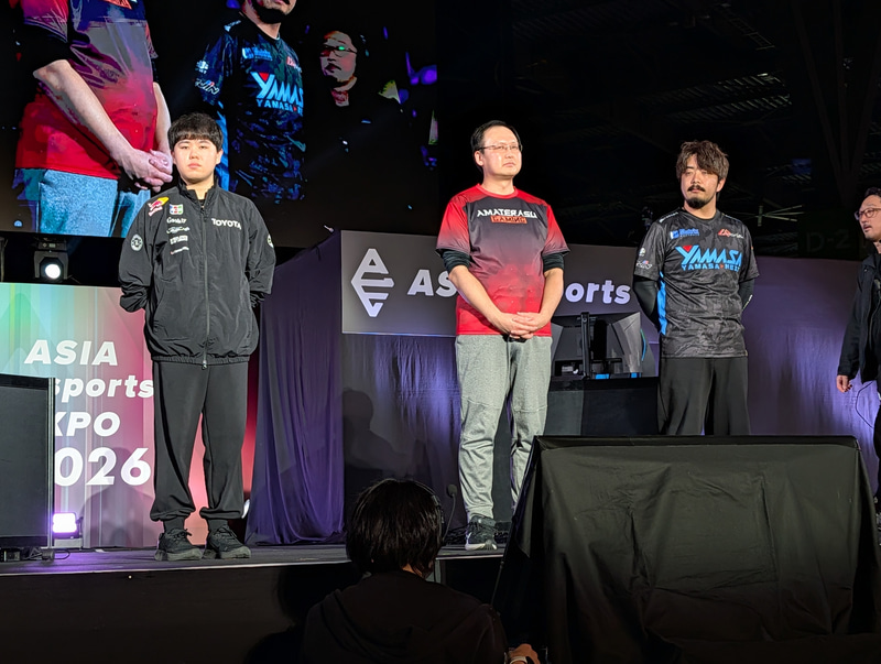 ステージ上に並ぶ「対戦格闘団体戦」日本代表の3人