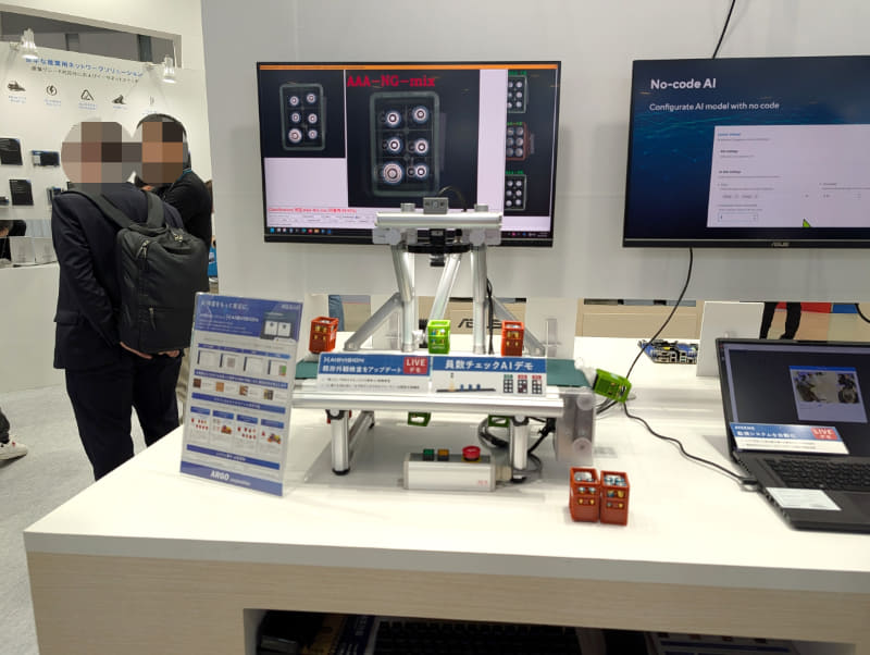 工場などで見かける高精度な外観検査の仕組みをプログラミング不要で実現するAI検査支援ソリューション「AISVision」のライブデモは100均ショップなどで見かける酒瓶ケースのミニチュアに単3電池を入れたものを使って実施