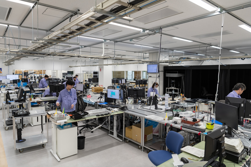 修理作業の様子。技術者が丁寧に作業し、故障情報の取得・分析や品質保証部門等へ情報共有を行なう