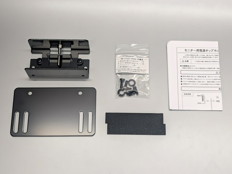 パッケージ。電源タップを挟むホルダー(左上)と、VESAマウントに取り付けるプレート(左下)を中心に、ネジ類、クッションシートなどで構成される