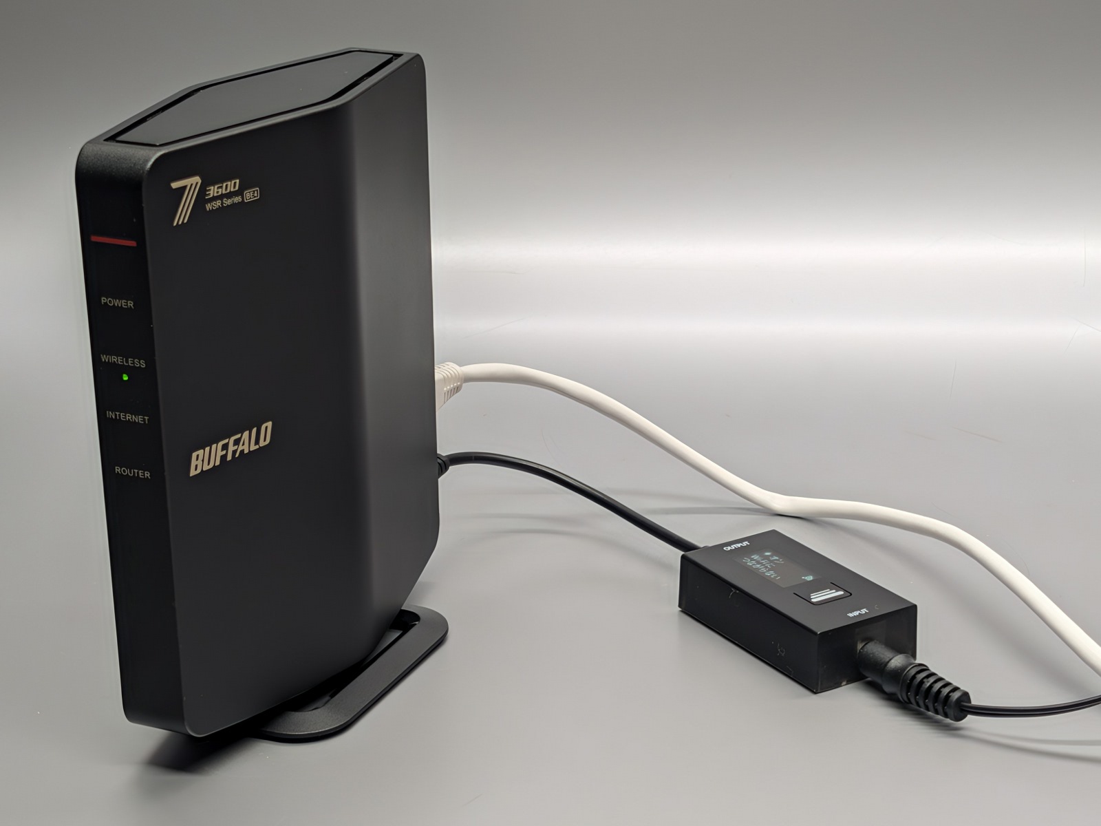 本製品装着後。ルーターと電源ケーブルの間に本製品を挟み込む形で取り付ける