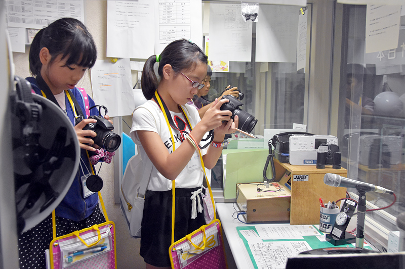 懸命に写真を撮る小学生記者。隣のブースもガラス越しに見えるようになっている