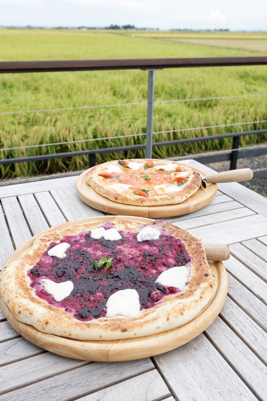 米粉生地によるピザ。奥がイタリア産モッツァレラチーズと農園で作ったトマトソースによる「トネリコピザ」で、手前が同じく農園のブルーベリーを使った「フルーツピザ」