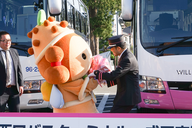しばっこくんがこれから発車するバスの乗務員 本田一修さんに花束を贈呈
