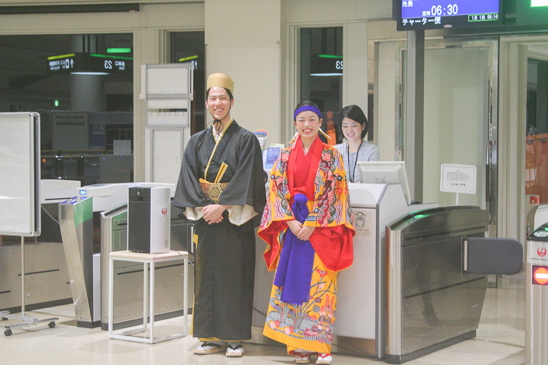 那覇空港の出発ロビーでは琉装に身を固めたスタッフが搭乗客との記念撮影に対応していた