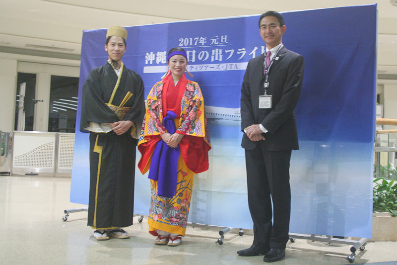 日本トランスオーシャン航空株式会社は、2017年1月1日に初日の出フライトを実施。出発前にはセレモニーが開催された。出発ロビーには記念幕を設置。同社代表取締役社長である丸川潔氏（写真右）と、琉装に身を固めたスタッフが登場