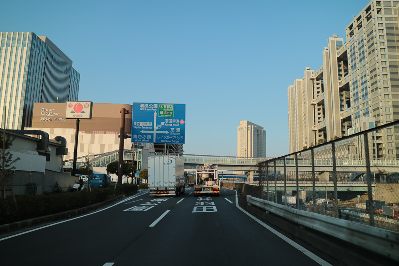 お台場中央交差点の車線は、両側に右左折レーンができ、中央の2車線が直進だが、首都高と潮風公園は左の車線。右車線は国道357号のトンネルを向かい、大井や羽田空港へ向かう