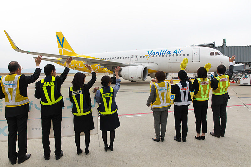 飛行機に向かって手を振るバニラエアのスタッフ