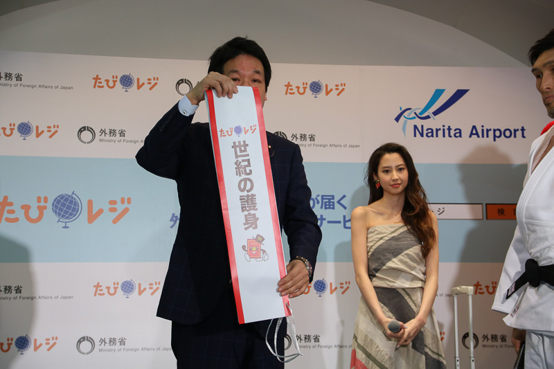 薗浦副大臣が手渡すタスキ