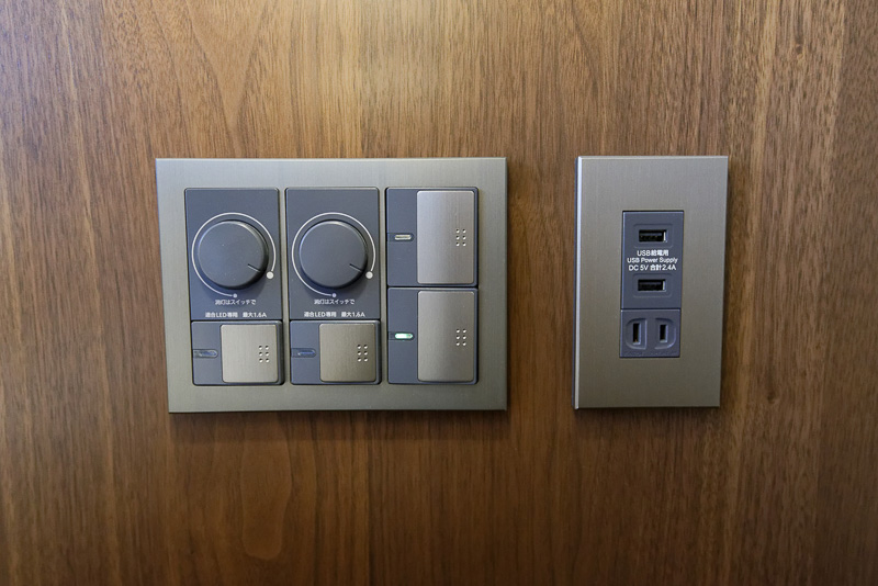 ベッドルームの枕元にあるスイッチ類と壁面コンセント