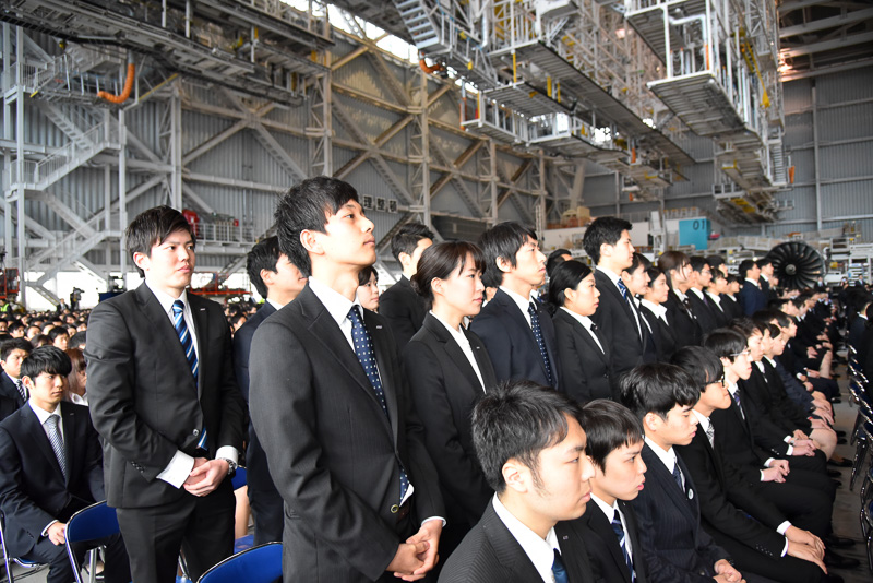 会社名が呼ばれ、名前が一斉にスライドに映し出されると新入社員たちが立ち上がった