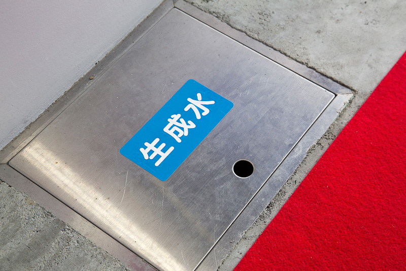 走行するとFCV同様、水が生成されるが、FCフォークリフトは清潔な倉庫内で使用するので水とはいえ車外に放出できない。そこで貯水タンクも装備していて、水素充填時に専用ホースをつなぎドレンから排出。生成水は排水溝へ流される