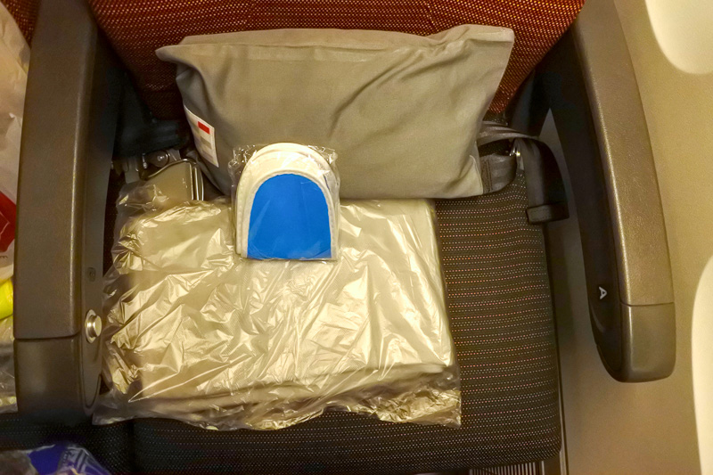 「新・間隔エコノミー（JAL SKY WIDER）」を採用したシート。座席には、枕、毛布、スリッパとともに鶴丸マーク入りのヘッドホンが用意されている