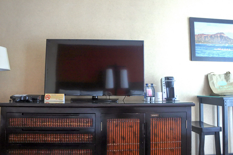 ベッドの目の前には大型の液晶テレビ。チェストの向かって右側に空の冷蔵庫とグラスなどが入っている