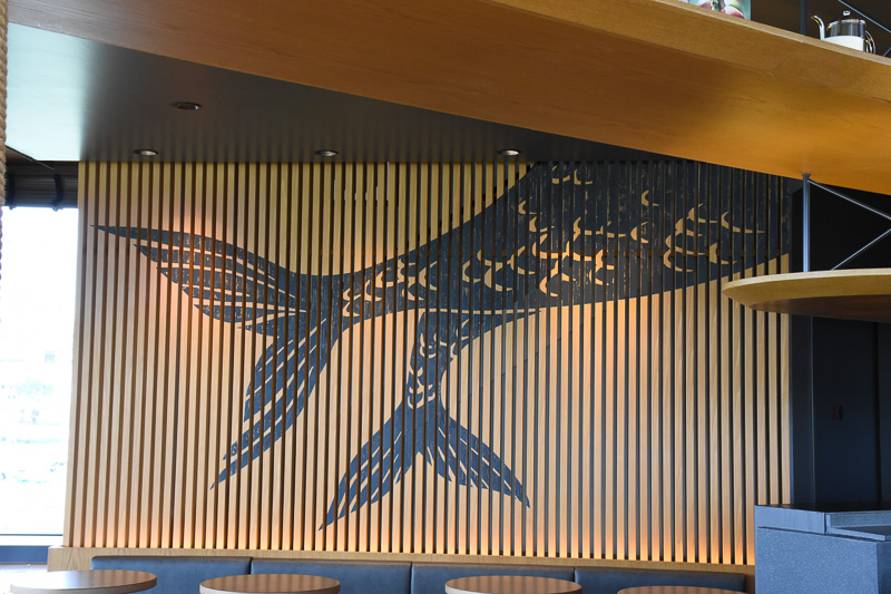 ルーバー状の装飾にはロゴのサイレン（セイレーン）が上下（1階と2階）に分かれて描かれており、上半身には神戸とシアトルの町並みも