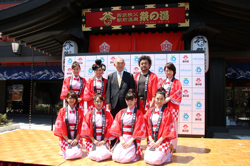 西武リクリエーション株式会社 代表取締役社長 布留川信行氏（後列中央）を中心に、右がパパイヤ鈴木さん、左がジャスミンさん、そのほかは祭の湯ガールズ