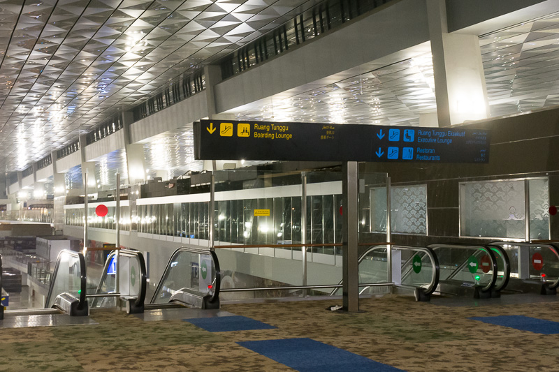 入国審査を過ぎると、搭乗口へ向かうエスカレータへ。1つは中2階（メザニン）へ、1つは2階の搭乗ロビーへ下りる