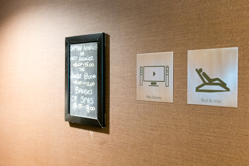 ビジネスラウンジ内のミニシアター。上映作品はラウンジ入り口とシアターの入り口に掲示。ディスプレイの脇に大きな時計がある