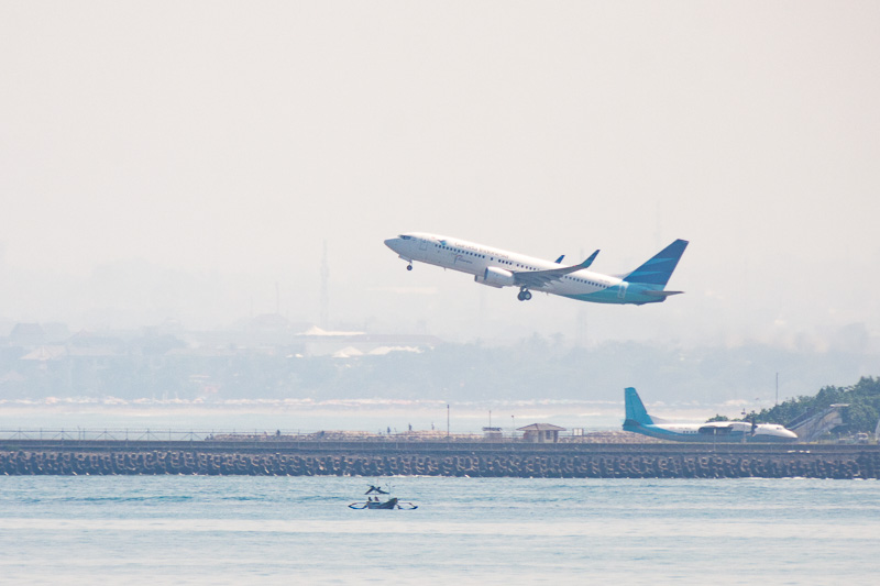 霞がかった空気で条件はあまりよくなかったが宿泊したヴィラから、ングラライ国際空港の滑走路を撮影。ニコン D7200とシグマ APO 50-500mm F4.5-6.3 DG OS HSMの組み合わせで撮影。写真上は水平が取れていないが500mmまでズームインして撮影したもので、距離感はつかめると思う。写真下はトリミングしたもの