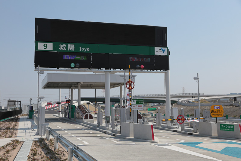 料金所のバーが上がりグリーンのシグナルが点灯、作業車を先頭に一般車両が入っていく