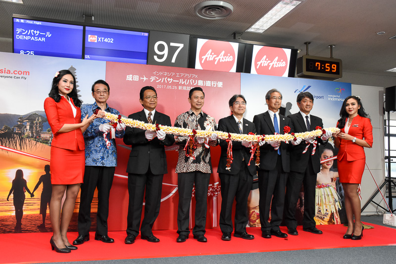 CA（客室乗務員）2名に囲まれて、テープカットならぬレイカット。左から、インドネシア共和国 ビジットインドネシアツーリズムオフィス 本地区事務所 代表 成田忠彦氏、駐日インドネシア共和国 ヘッドオブコミュニケーション バンバン・エコ・プリセント氏、インドネシア・エアアジアX CEO・キャプテン スリスティオ・ヌグロホ・ハヌング氏、国土交通省 東京航空局 成田空港事務所 成田国際空港長 木村茂夫氏、成田国際空港株式会社 代表取締役副社長 斉田正己氏、スイスポートジャパン株式会社 成田空港支店長 伊藤雅道氏