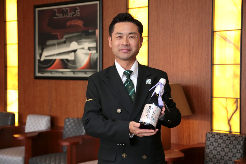「聚楽第大吟醸エクストラプレミアム」を手にする支配人 樺山高弘氏。乗客へのサービス全般の責任者を務める