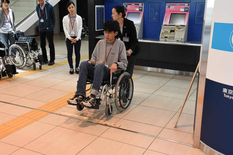 木の板を使って段差の乗り越え方を学ぶ。車椅子後部の突起を足で押して前輪を持ち上げる。このときも事前の声かけを忘れない