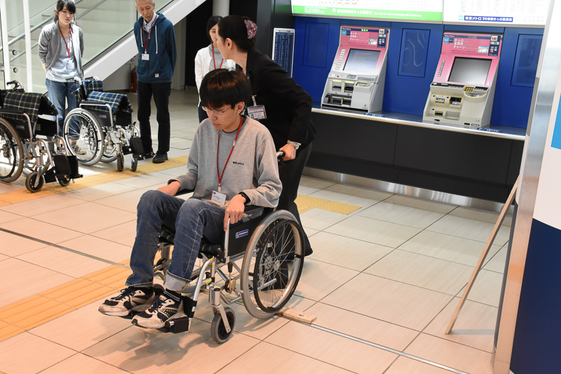 木の板を使って段差の乗り越え方を学ぶ。車椅子後部の突起を足で押して前輪を持ち上げる。このときも事前の声かけを忘れない