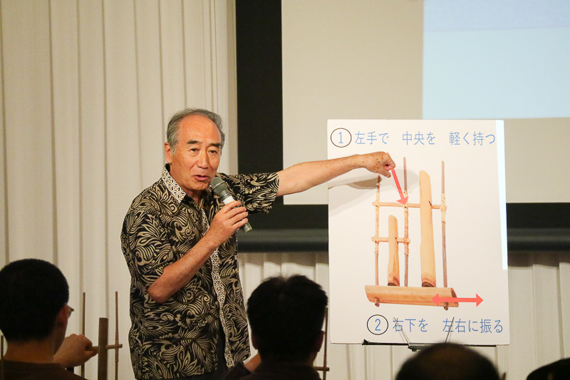 神戸インドネシア友の会 KISアンクルン代表の森井國興氏が、セミナー参加者にアンクルンの演奏を説明