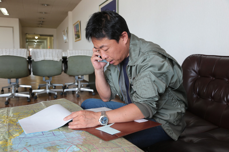 フライトプランを電話で伝える。「（機体のカラーは）ホワイト…ウィズ、キャラクター？」