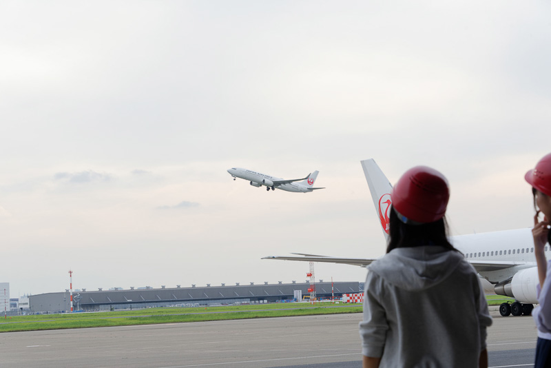 格納庫の前で、近くの滑走路から離陸していくJAL機を見守った