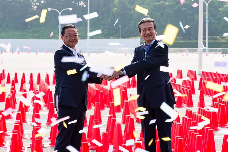 祝福のリボンが舞うなかで握手を交わすオリエンタルランド 上西社長とダイハツ 三井会長