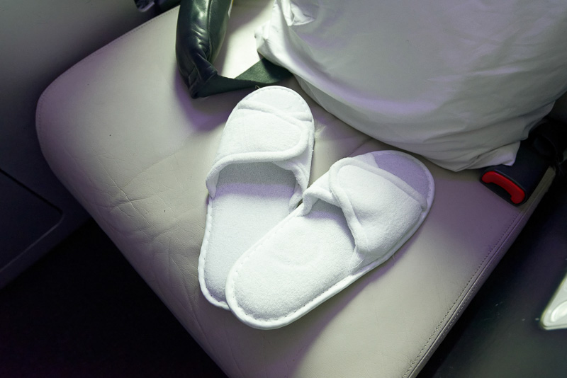 機内用スリッパ、ヘッドフォン、アメニティ類が用意されている