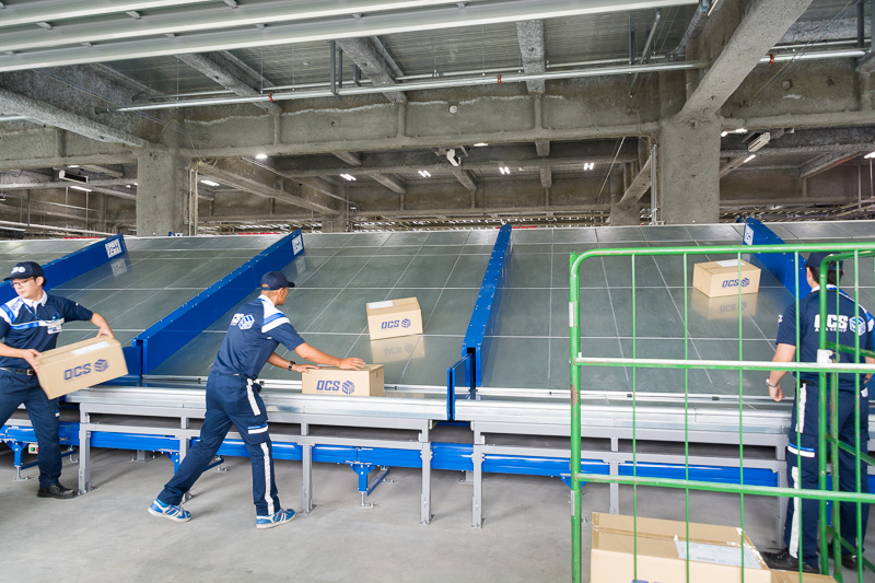 3台目のバーコードリーダーで郵便番号を識別し、行き先別に荷物をシュート。クルーが集配車へ積み込んでいく