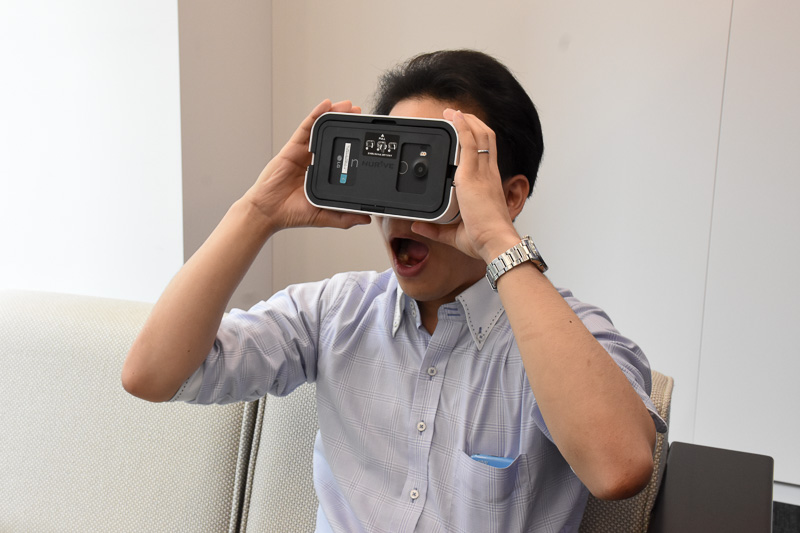 ナーブのVRヘッドセットを構える髙橋氏。VRヘッドセットは、重さや締め付けを感じやすい“ヘッドマウント型”をあえて避けて、手で保持するスタイル